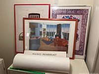 View of three framed prints and one rolled unframed print on a table to show overall lot.