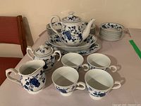 Photo showing most items in set including teapot on oval plate, creamer, sugar container, and four teacups arranged in front with stacks of appetizer plates, dessert bowls, and saucers behind.