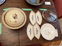 Set displayed on table showing all items including the lidded pot, four blue floral patterned shallow bowls, decorative plates both oval and round.