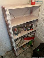 Photo of 4 tier metal shelving unit with assorted items including power bars, extension cords, tapes, glue, and tools