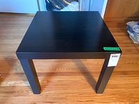 Front view of the black square Ikea side table on hardwood floor.