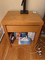 Front view of one table showing closed drawer and bottom shelf with books