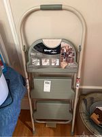 Photo of folded StepRight 3-step utility stepladder with label showing weight capacity and features.