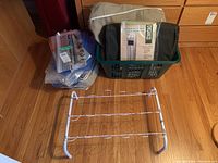 Black storage bin with hanging closet organizer and vacuum seal bags inside, white metal shoe rack on floor