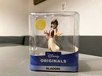 Front view of Aladdin figurine in clear plastic box with blue base labeling 'Disney Originals Aladdin'. Figure appears new and undamaged, box shows dust.