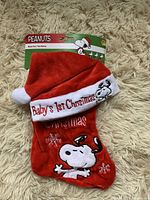 Photo of new with tag red Baby's First Christmas stocking and hat featuring Snoopy embroidery