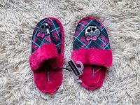 Top-down photo of the Monster High kids fuzzy slippers showing the decorative skull and bow pattern and pink fuzzy trim.