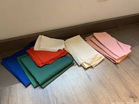 Photo of pile of folded cloth napkins in various colors including blue, green, red, white, cream and pink.