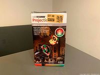 Front view of the sealed box showing brand, product image, and features including lightshow effects projecting Santa and colorful lights.