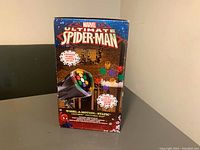 Box packaging of Marvel Ultimate Spider-Man Christmas light projector showing product name and colorful light effects.