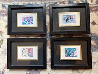 Top-down photo showing all four framed reproductions lying on carpet. Frames are black, sized approximately 7x9 inches. Artworks are colorful abstract prints.