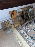 Four stained glass mirrors of various sizes placed on carpet and against a wall, showing the overall set and visible blue tape on cracked corner.