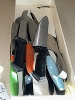 Top-down photo of a set of knives with various handle colors in a drawer.