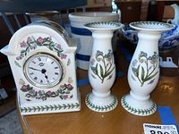 Front view of the ceramic clock and pair of candleholders showing floral designs and clock face