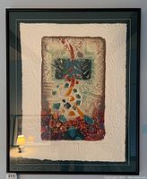 Framed abstract fiber art print with embossed paper and multi-colored painting in blues, reds, and oranges.
