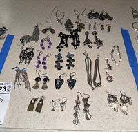 Multiple pairs of assorted earrings spread out on table, showcasing various shapes, colors, and materials including beaded and metal designs.