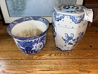 Blue and white ceramic planter featuring Abbey architectural pattern and Asian style garden stool with bird and floral motifs on wooden floor.