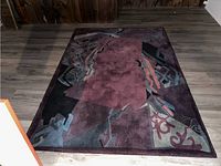 Full view of the rectangular rug showing the burgundy center and abstract geometric design