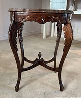 Front and side view showing carved apron and ornate curved legs with cross stretchers and finial