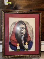 Framed portrait of woman in red hood with two lit candles in foreground, detailed close-up shows brushstroke and shading details.