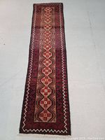 Full-length view of narrow runner rug laid flat on floor showing overall design and condition