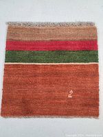 Top view of the square Persian Gabeh Shiraz wool rug with horizontal stripes in brown, red, green, and rust tones.