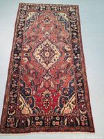 Full frontal view of rug laid flat, displaying central medallion, field and border design.