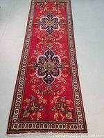 Overall view of runner rug face showing red field, central medallions and border