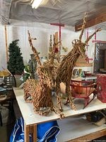 Two grapevine deer yard decor figures, showing the standing deer and the lying deer on a table in a workshop environment.