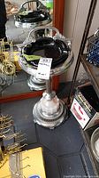 Floor standing ashtray with reflective metal parts, ribbed column, and milk glass decorative section near the base. Missing attached handle visible in photo.