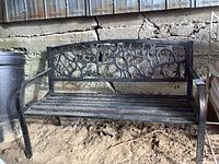 Front view of bench showing decorative vine-pattern backrest and slatted seat