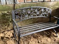Front and side view of metal garden bench showing leaf pattern on backrest and slatted seat.