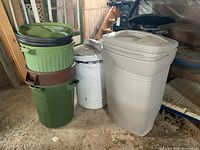 Photo showing all five garbage bins grouped inside workshop space with a dirt floor and old wooden stairs in background.