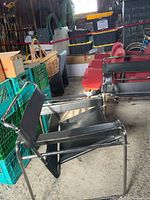 Side view of one chair showing tubular chrome frame and black faux leather seat straps