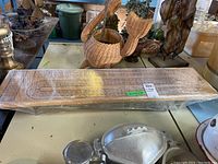 Top view of the cribbage board table showing the entire length with multiple cribbage tracks and numbers visible under cling wrap.