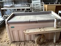Front and side view of Jardin resin outdoor deck storage box, showing brand label and weathered condition.