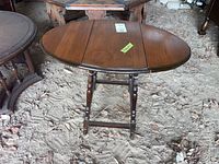 Oval wooden drop leaf table with both leaves extended, showing the wood grain and finish.