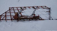 Overview of metal harrow attachment lying on snow-covered ground