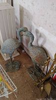 Front view of both heron statues side by side on workshop floor