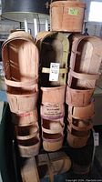 Stacked wooden orchard produce baskets with handles, showing weathered wood, text markings, and different printing styles on baskets.