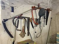 Full view of various hand tools, saws, and welding mask hanging on the workshop wall.