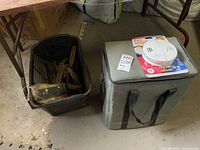 Gray soft cooler bag with black handles, Yamaha manual and Kidde smoke alarm on top