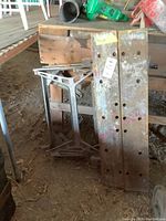 Photo showing the full workbench folded with wooden panels and metal frame on a dirt floor surrounded by shed tools.