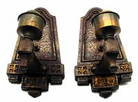 Pair of antique metal wall sconces showing front view, hammered texture, floral decoration, and bulb cups