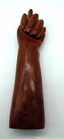 Photo of the upright wooden hand carving showing the front of the clenched fist and forearm detail.