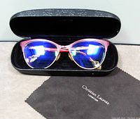 Glasses inside the black hard case with Christian Lacroix cleaning cloth seen in front.