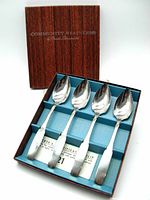 Set of four vintage Oneida stainless steel grapefruit spoons in original box with blue interior and brown exterior lid, inscriptions on lid.