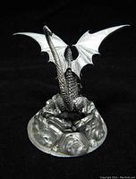 View of the dragon paperweight from the rear showing the textured wings, tail, and rocky base.
