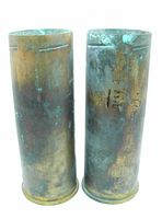 Pair of vintage artillery shell casings standing upright, showing patina and oxidation