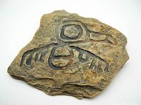 Front of the carved petroglyph stone tile showing detailed Indigenous style artwork resembling Norval Morrisseau's art